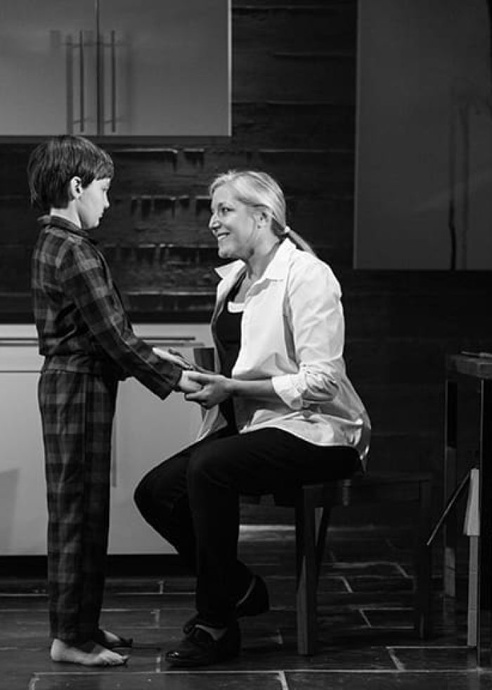 Woman and boy holding hands in a kitchen setting.