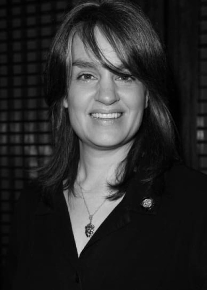 Pam MacKinnon smiling, wearing a black shirt and necklace