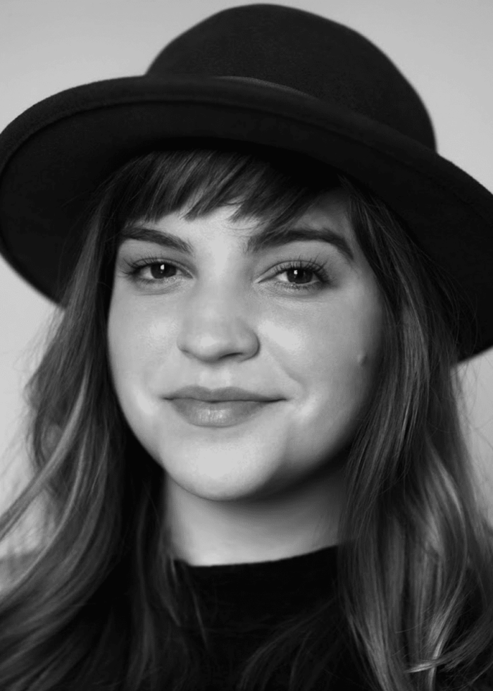 Young woman with a hat, smiling in a black and white portrait.