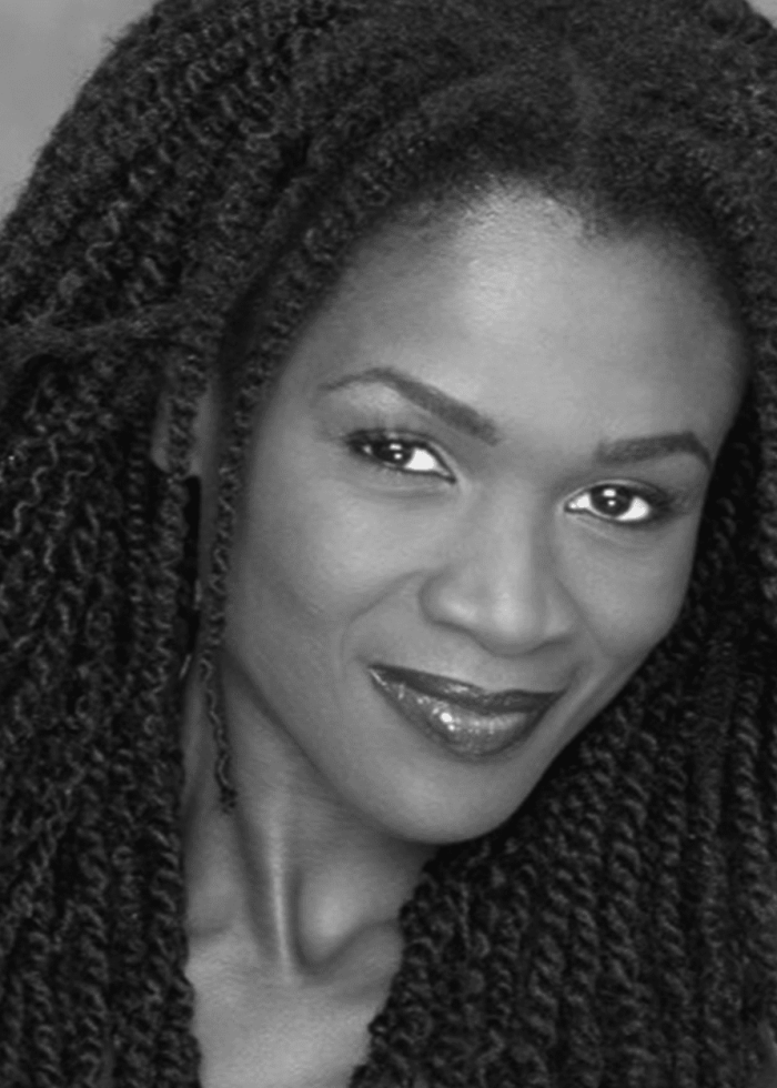 Patrice Johnson smiling, with long twisted braids and dark lipstick