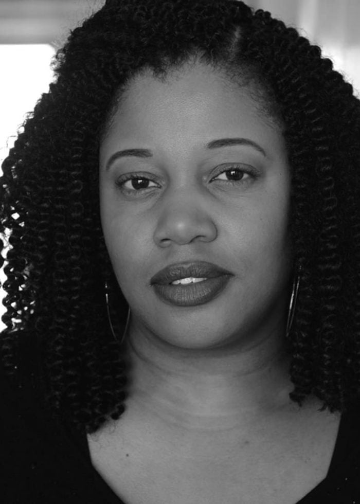 Pernell Walker looking directly at the camera with curly hair and hoop earrings.