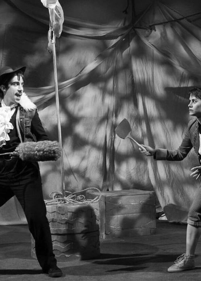 Actors in a scene from "The Pirate La Dee Da" play, one with a feather duster, one with a paddle.