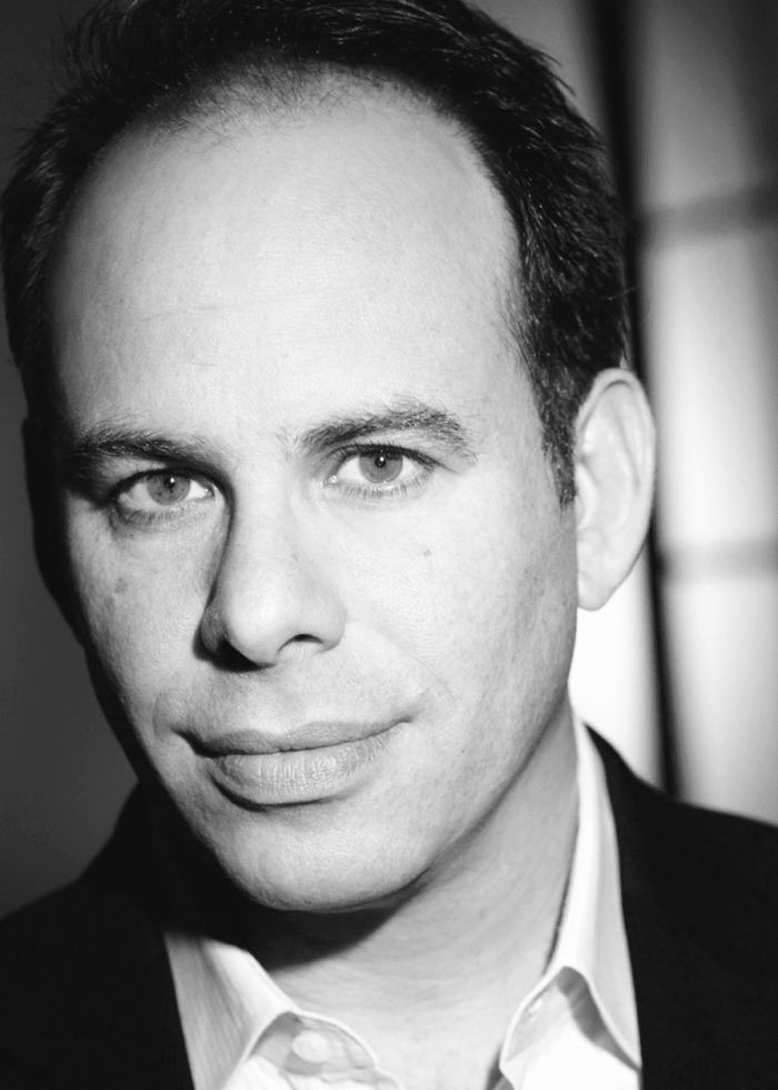 Andrew Polk, a man with dark hair in a suit, looking directly at the camera.