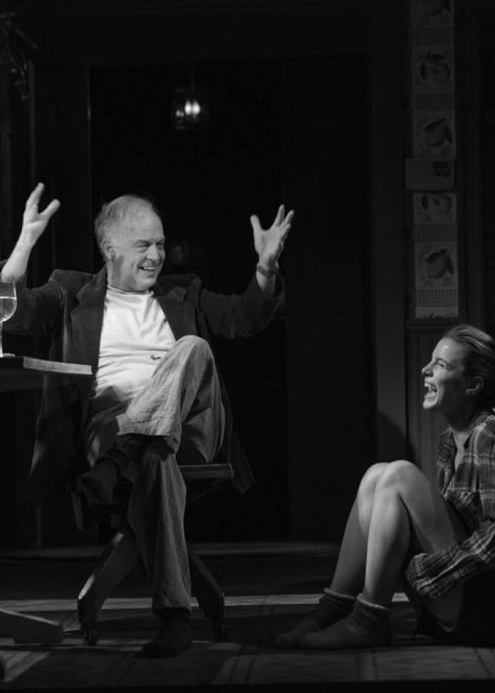 A man and woman share a laugh in a dimly lit room. An Uneasy Rapport.