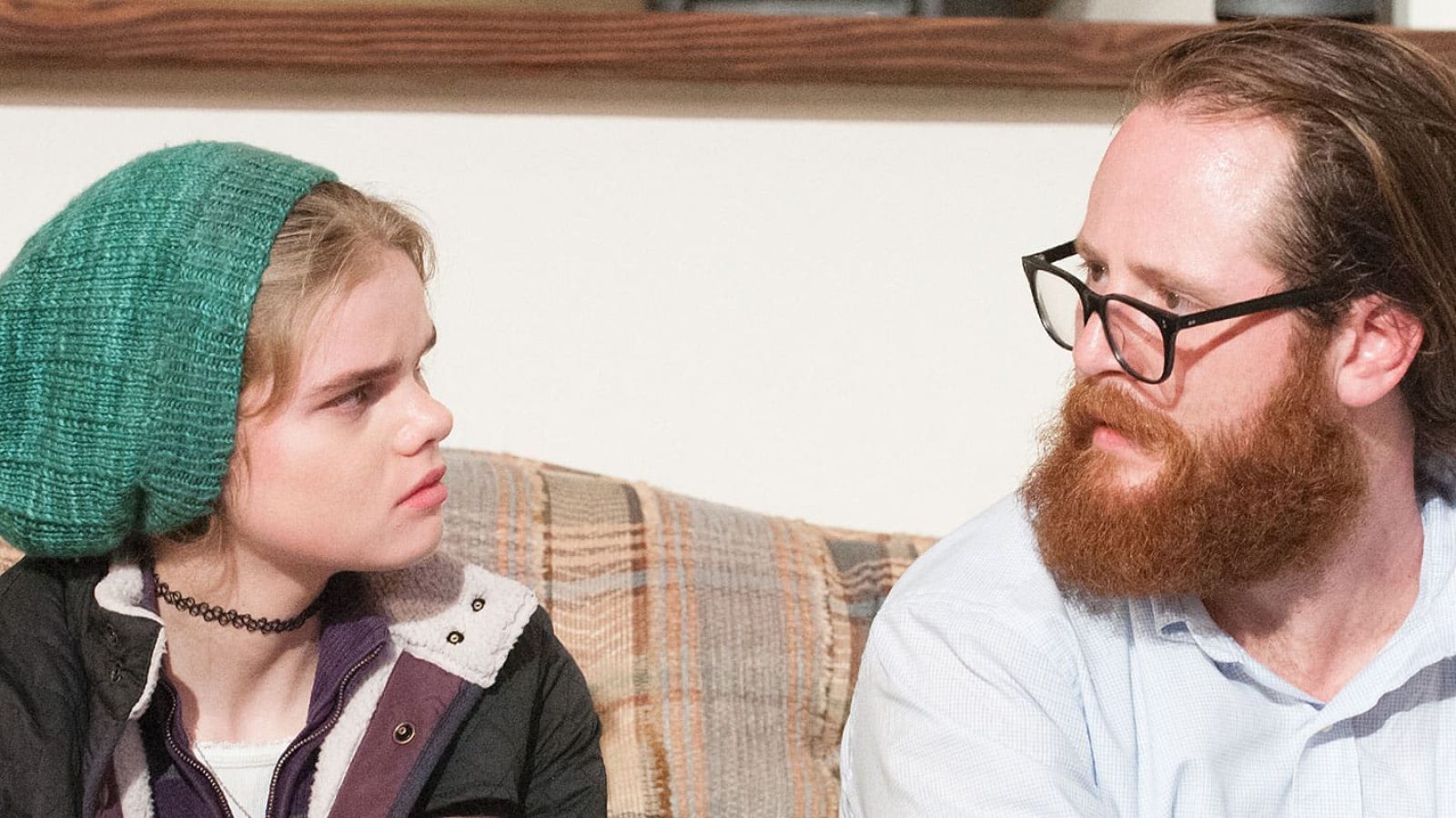 A young woman and a man with a beard have a serious conversation.