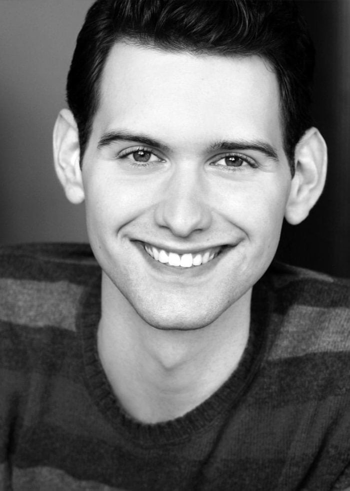 Quinn Corcoran smiling in a striped sweater, headshot