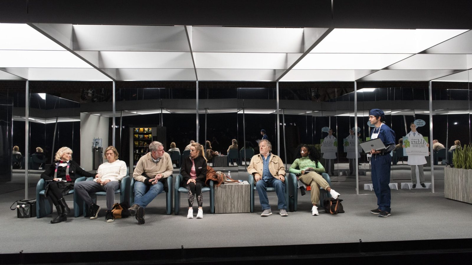 Patients wait in a sterile, mirrored waiting room. A doctor holds a laptop.