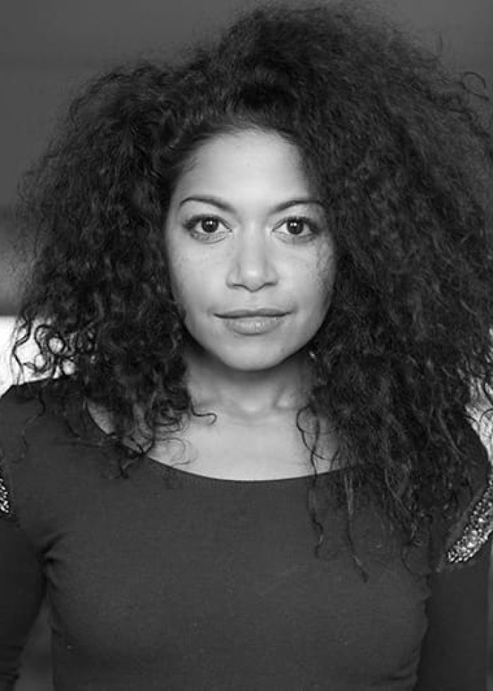 Rebecca Naomi Jones in a black and white headshot, looking at the camera.