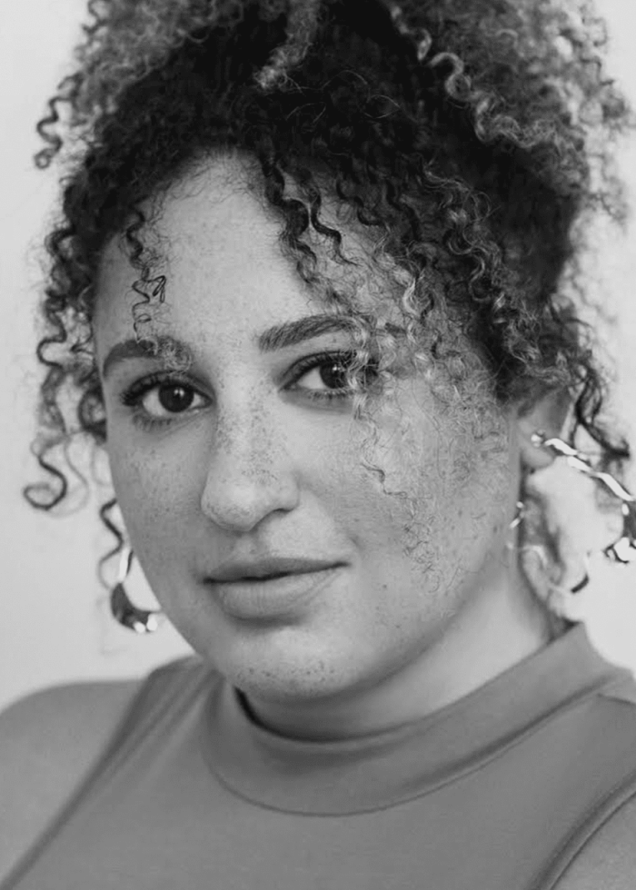 Simone Recasner portrait with curly hair and hoop earrings.
