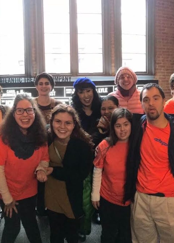 Group photo at a Relaxed Performance event; many people wearing orange shirts and smiling.
