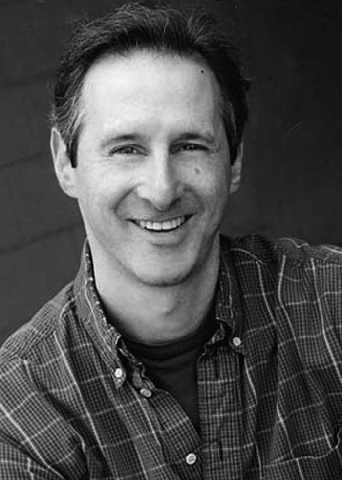 Richard Topol smiling in a plaid shirt