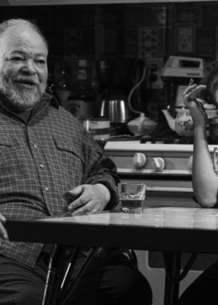 Off Broadway's "Between Riverside and Crazy": Man in wheelchair and woman at table with drinks.