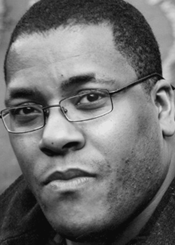 Close-up portrait of Roy Williams wearing glasses, looking directly at the camera