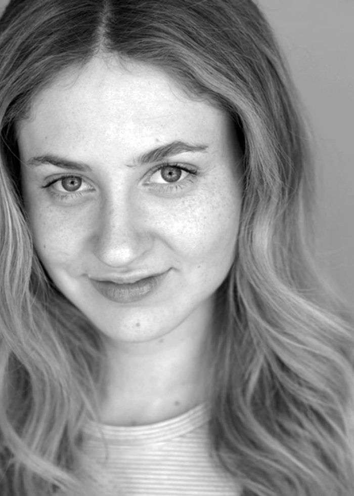 Close-up portrait of Ruby Frankel with long wavy hair and a slight smile.