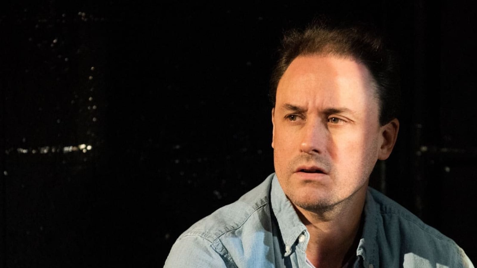 Man in denim shirt looking pensive, secrets implied.