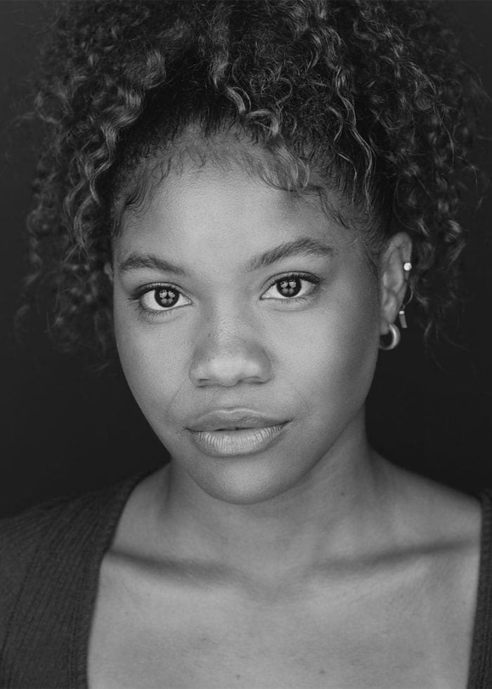 Sinclair Daniel, a young woman with curly hair, looks directly at the camera.