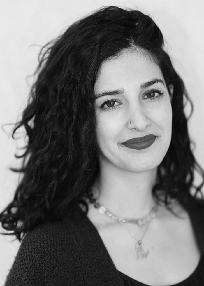 Sanaz Toossi portrait: smiling woman with dark curly hair and nose ring