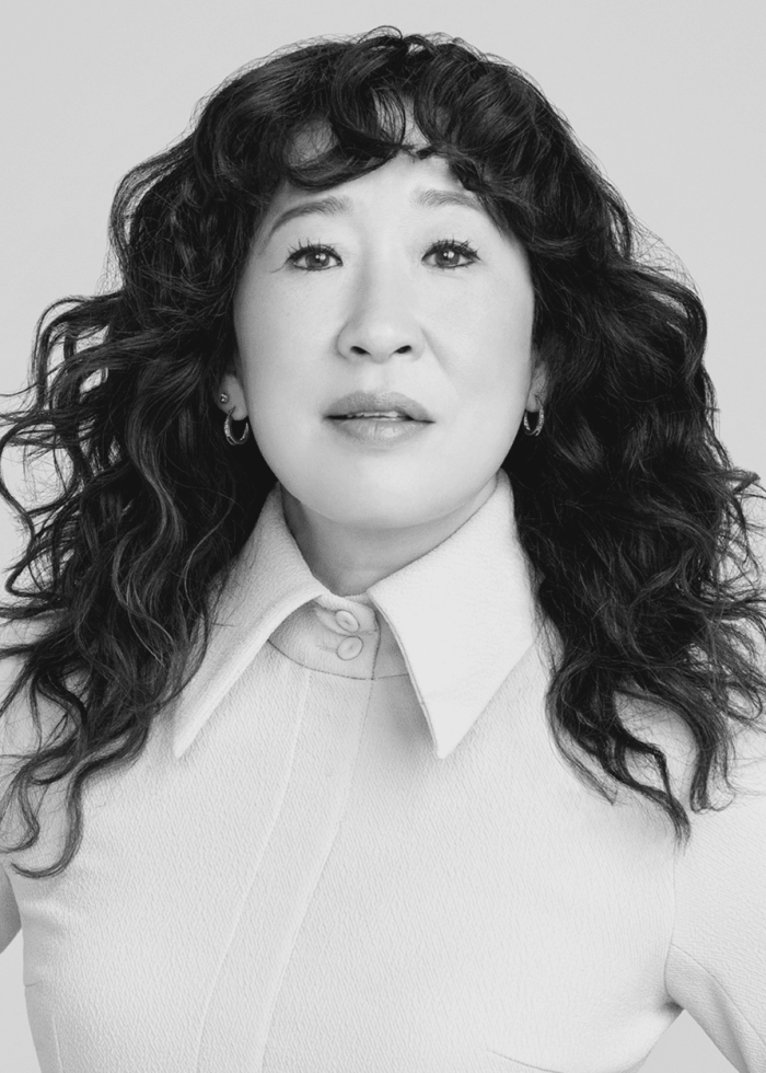 Sandra Oh in a close-up portrait, wearing a white collared shirt.