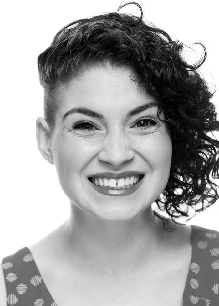Smiling woman with curly hair and shaved side
