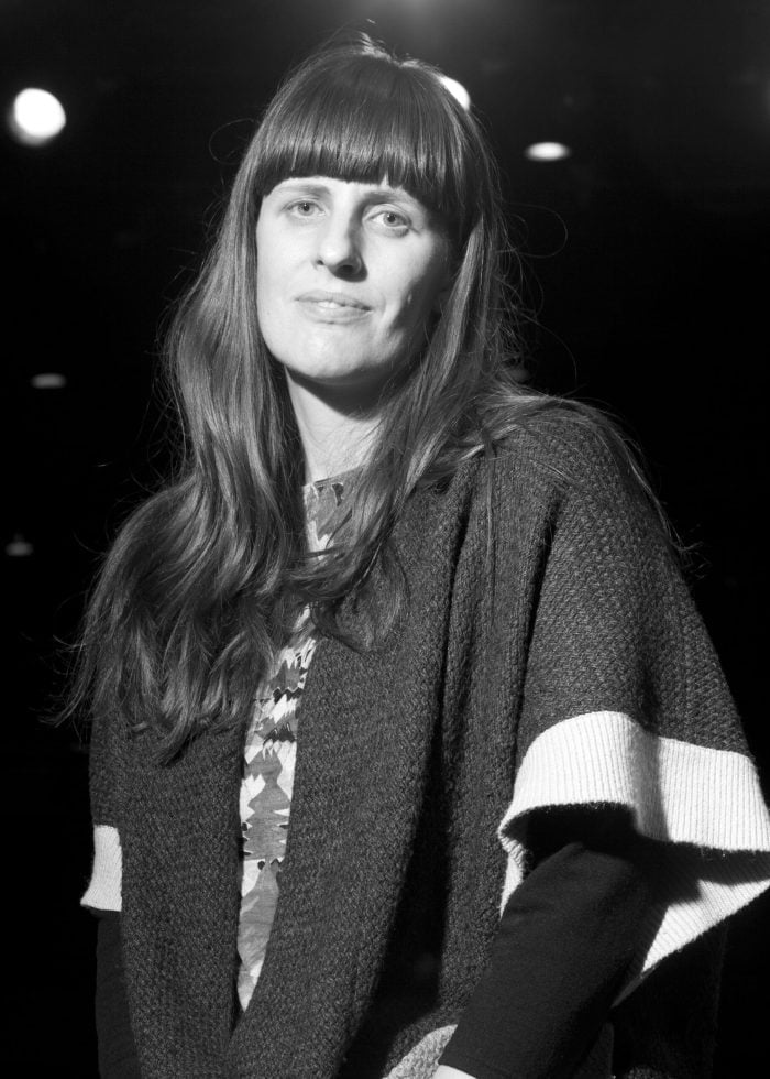 Sarah Benson portrait with long hair and bangs, wearing a sweater.