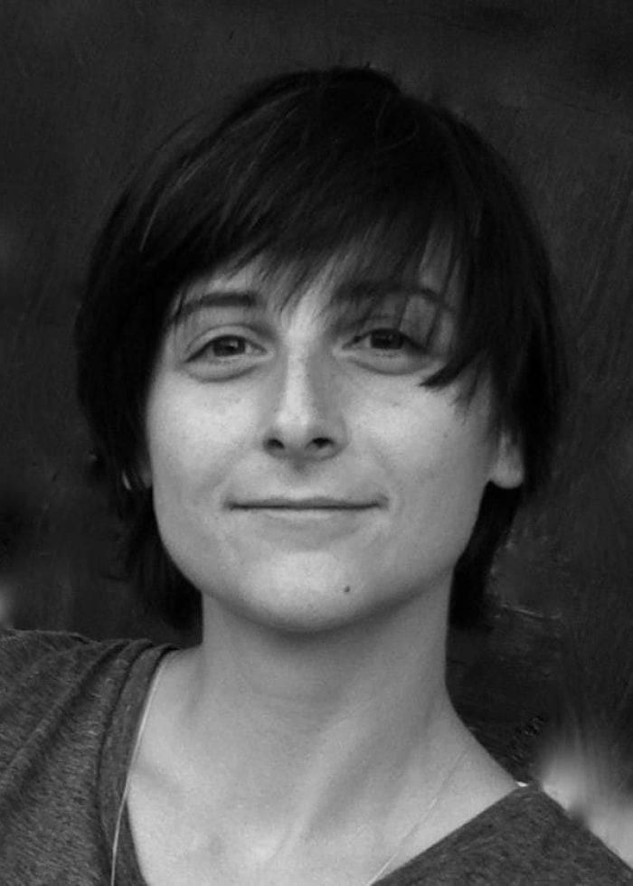 Portrait of Sasha Milavic Davies with short dark hair, smiling slightly.