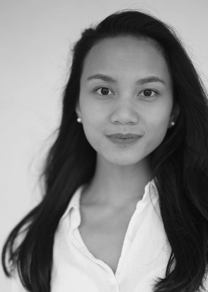 Portrait of Sienna Aczon, smiling, with long dark hair and a white shirt.