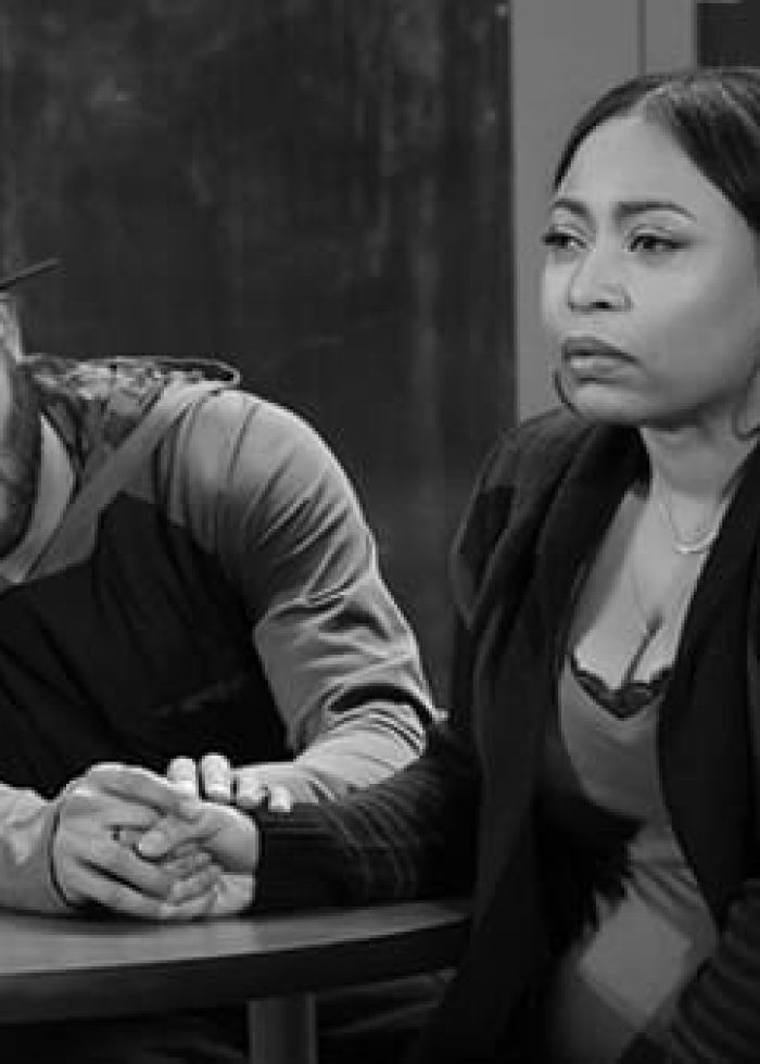 Man and woman holding hands, looking concerned. Black and white image.