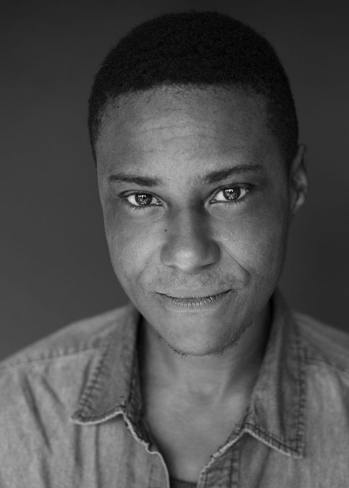 Portrait of TL Thompson, looking directly at the camera, wearing a denim shirt.