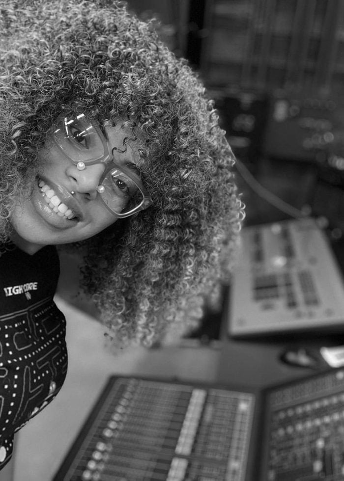 Twi McCallum smiling, wearing glasses, in a recording studio.
