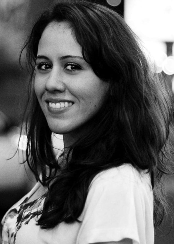 Smiling young woman with dark hair, wearing a white t-shirt