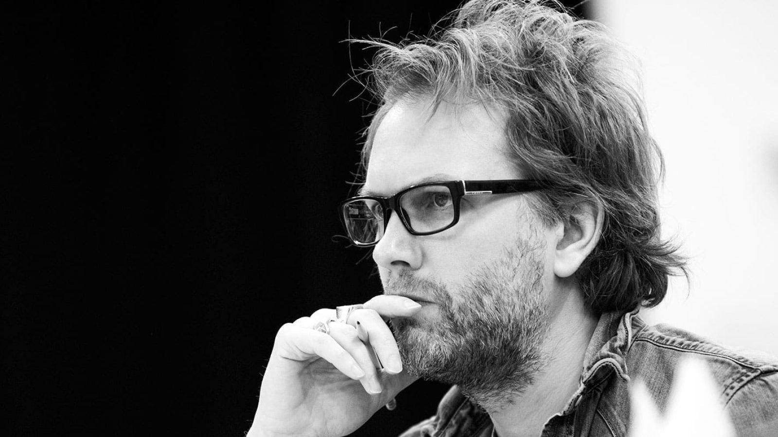 Man with glasses thoughtfully touching his chin