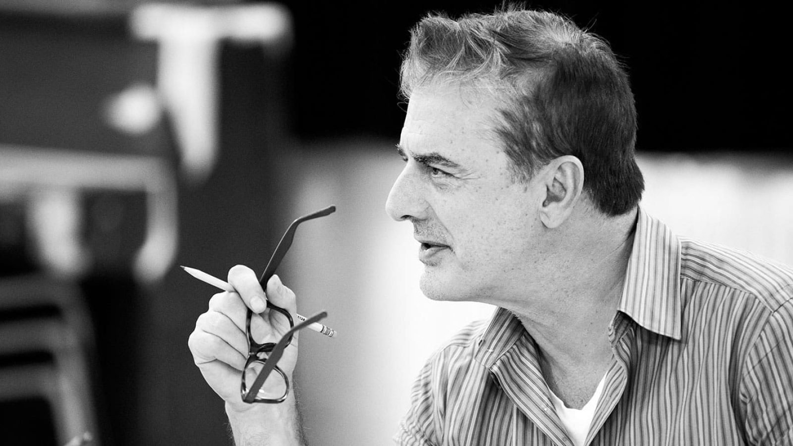 A man thoughtfully holds his glasses and a pencil.