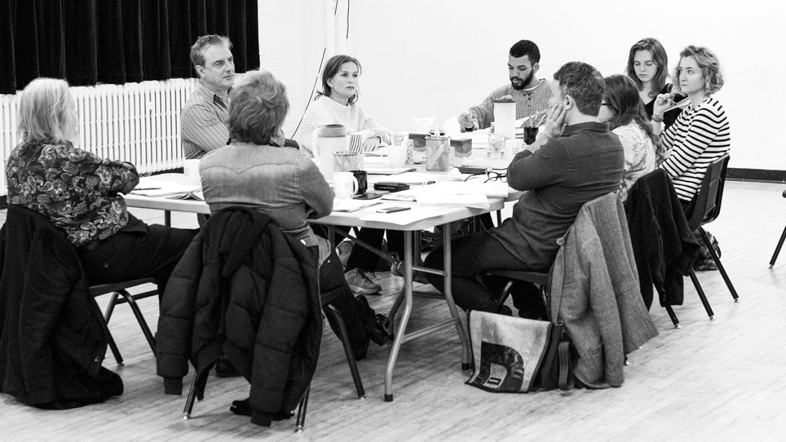A group of actors and directors gathered around a table, engaged in a discussion.