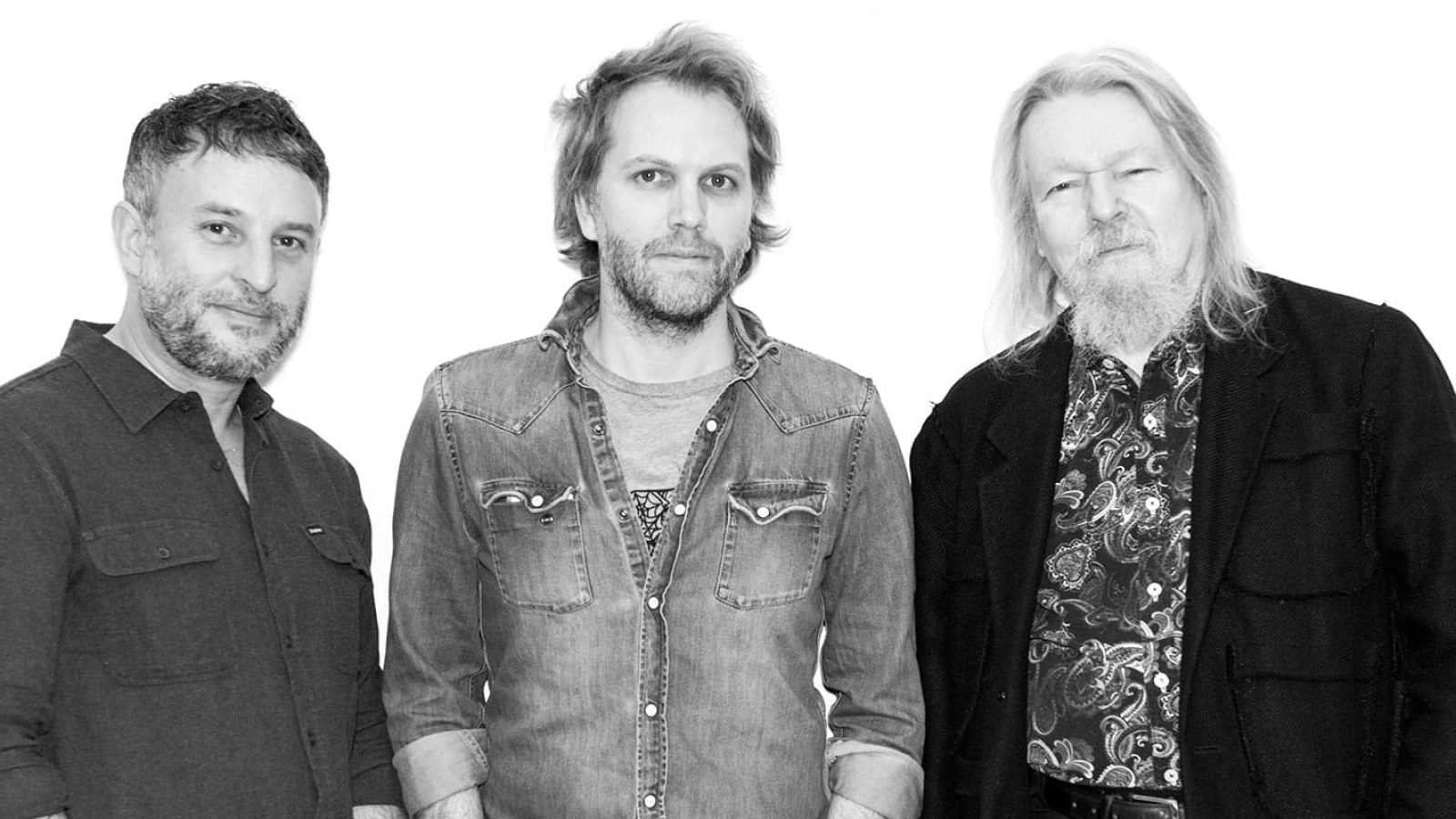 Three men, The Mother band members, posing for a photo.