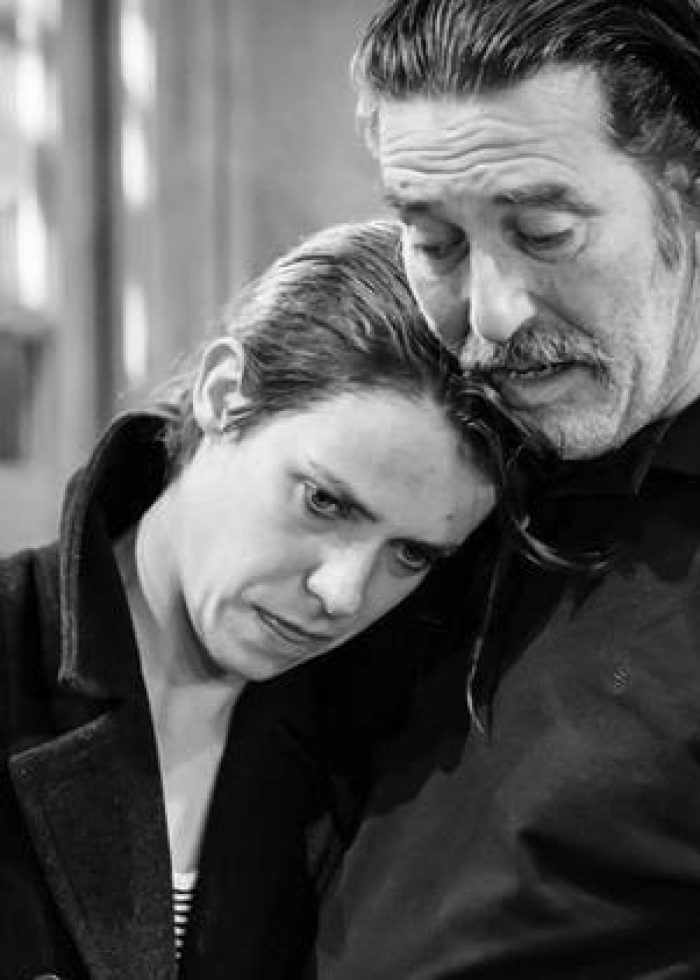 Two actors embrace in a scene from The Night Alive, a black and white theater production.