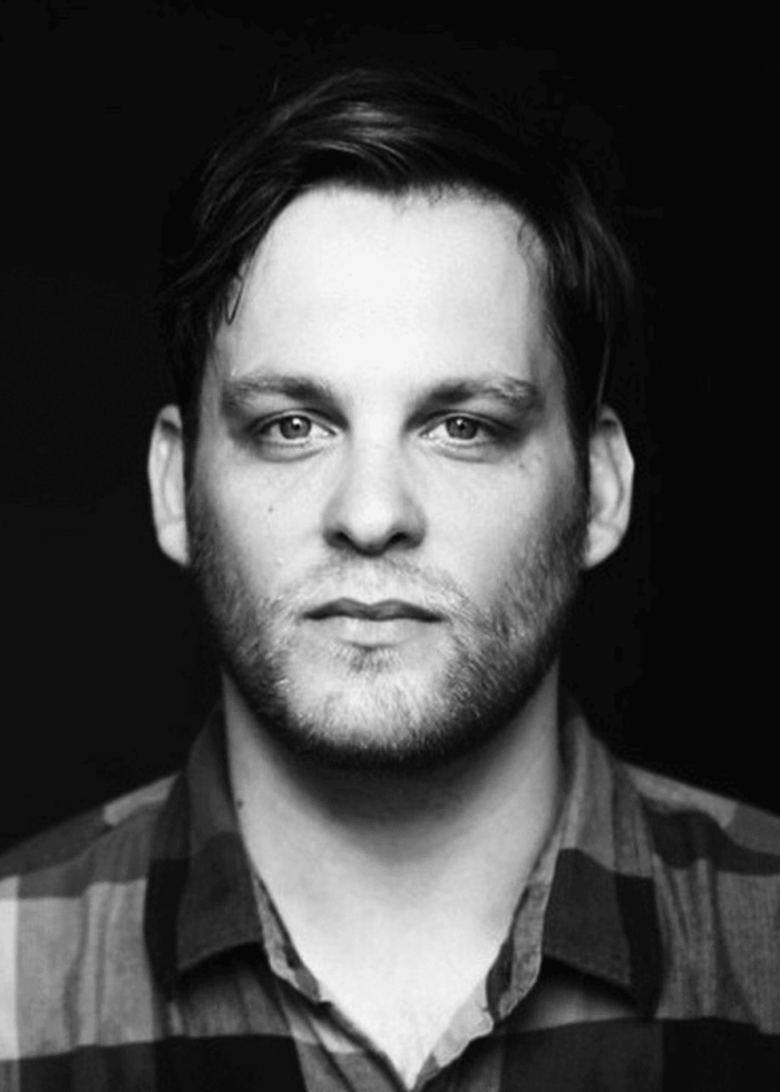 Theo Stockman looking directly at the camera, wearing a plaid shirt.