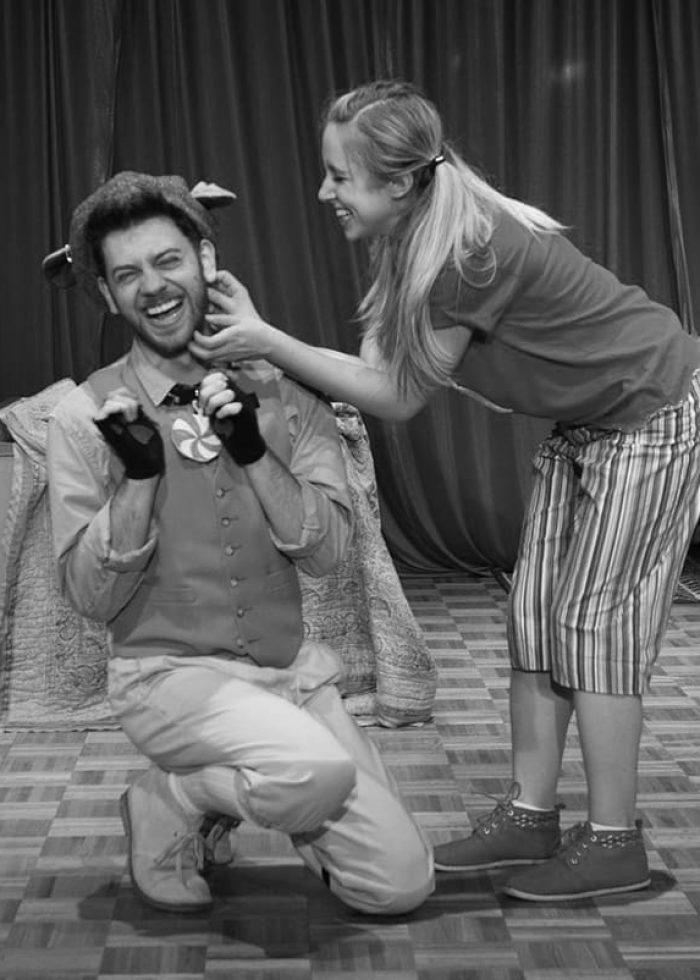 Actors laughing on stage, a playful moment during a performance.