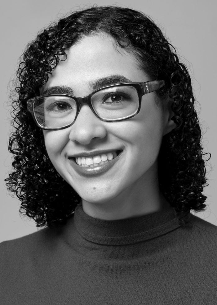 Smiling young woman with curly hair and glasses