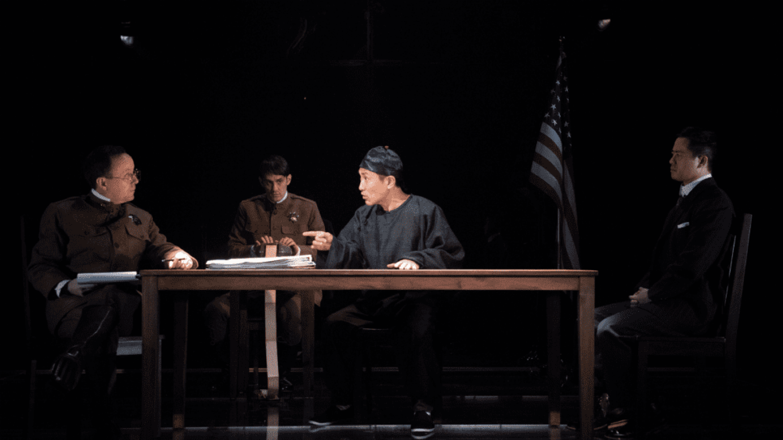 A tense courtroom scene in "The Far Country," featuring four individuals seated around a table.