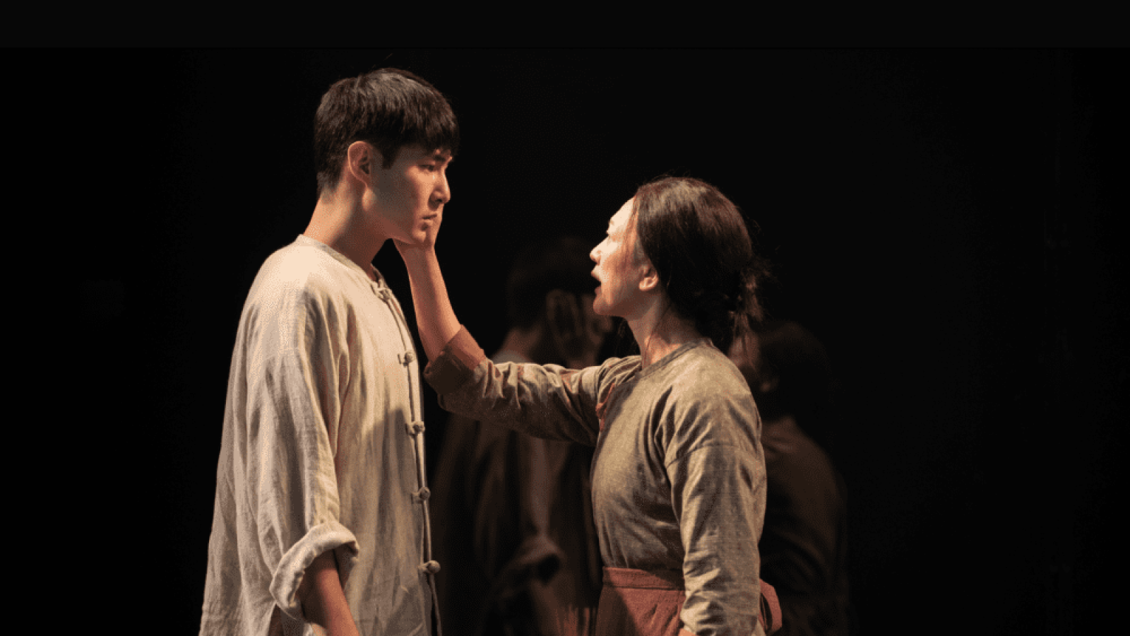 A woman gently touches a man's face, a poignant moment in the play, "The Far Country.
