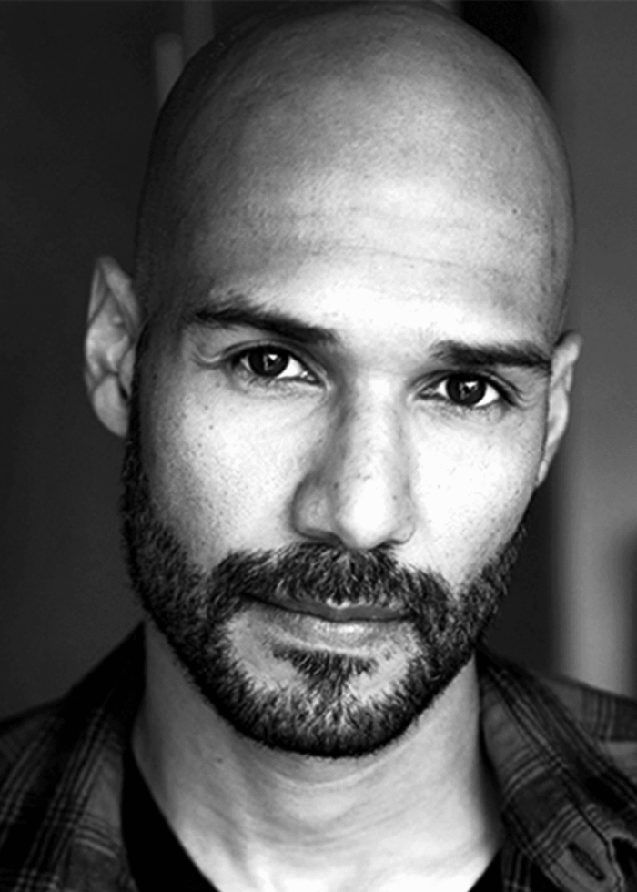 VegaLuis_headshotBW Close-up portrait of Luis Vega, a bald man with a beard, looking directly at the camera.