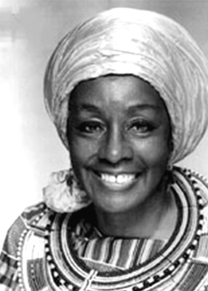 Vinie Burrows smiling, wearing a head wrap and patterned collar