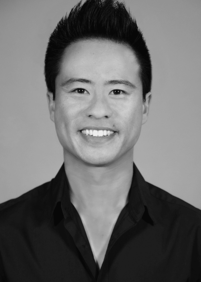 Whit K. Lee smiling, wearing a black shirt, with spiky hair