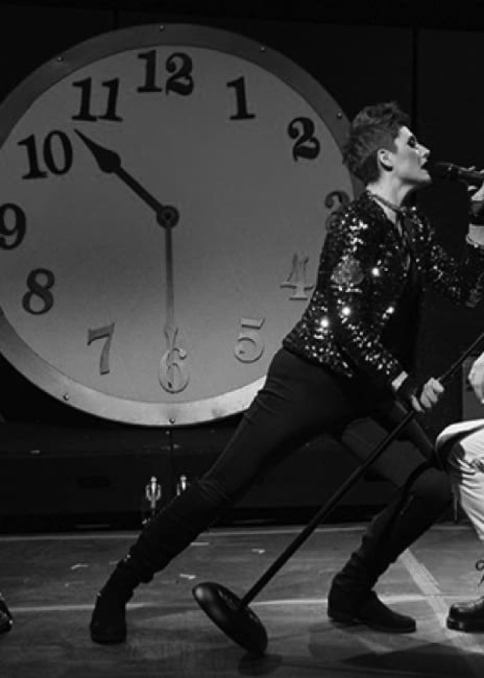 Rock band performing in Alice in Wonderland musical. Stage with large clock backdrop. Rock out!