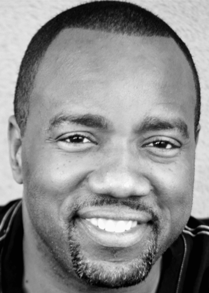 Malik Yoba smiling, close-up portrait in black and white