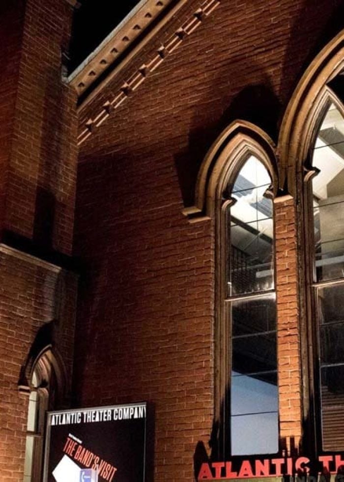 Atlantic Theater Company building exterior at night with Gothic windows and banner