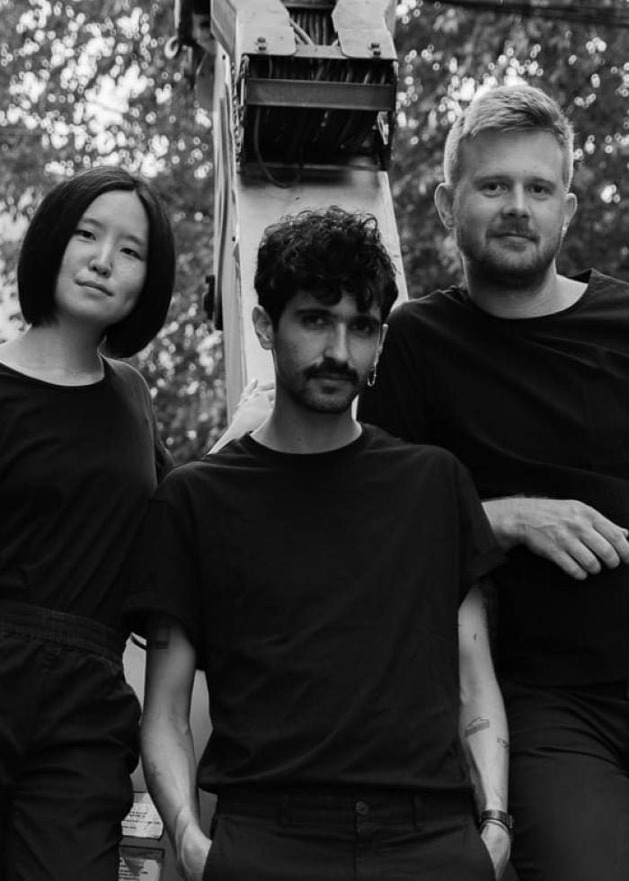 Three people in black clothing posing outdoors, dots