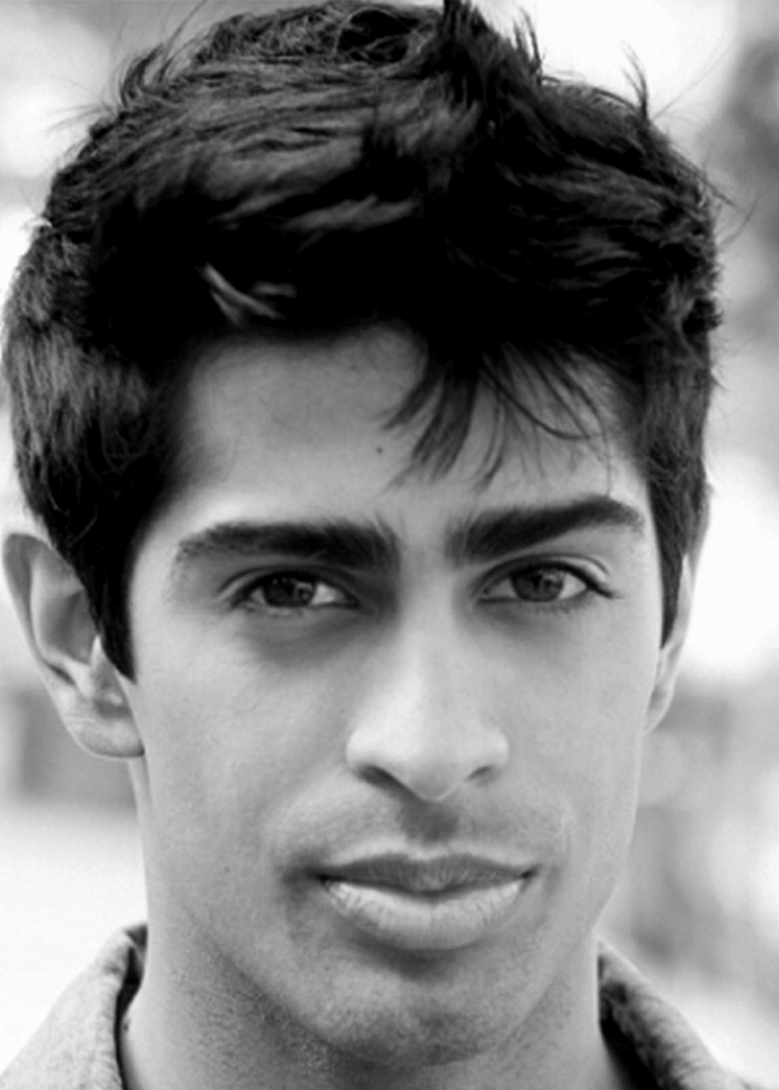 Close-up portrait of a young man with dark hair and eyes, looking directly at the camera.