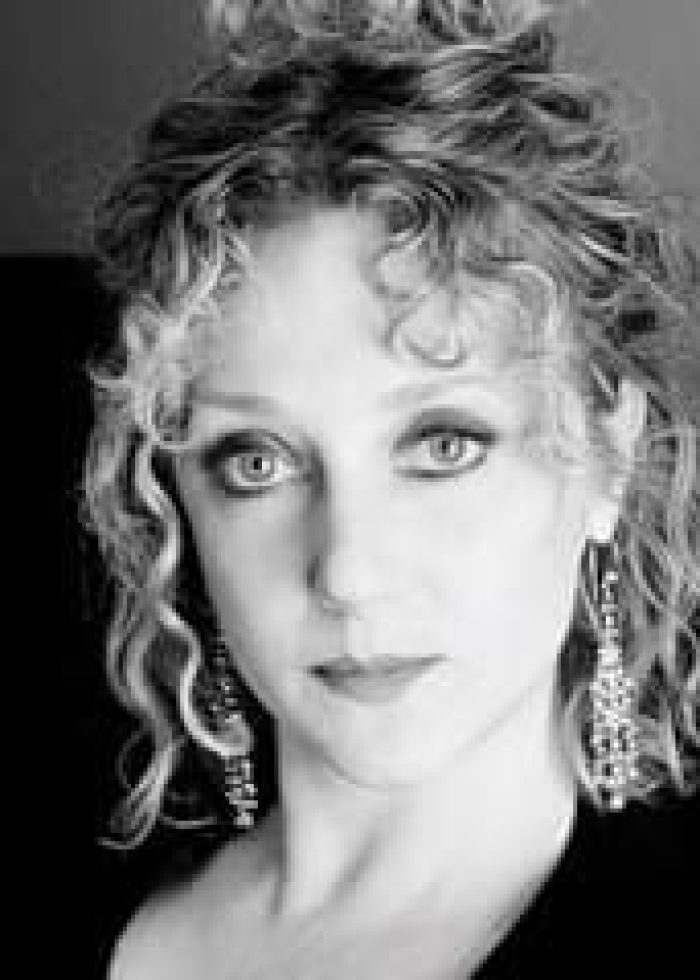 Black and white portrait of Carol Kane with curly hair and earrings.
