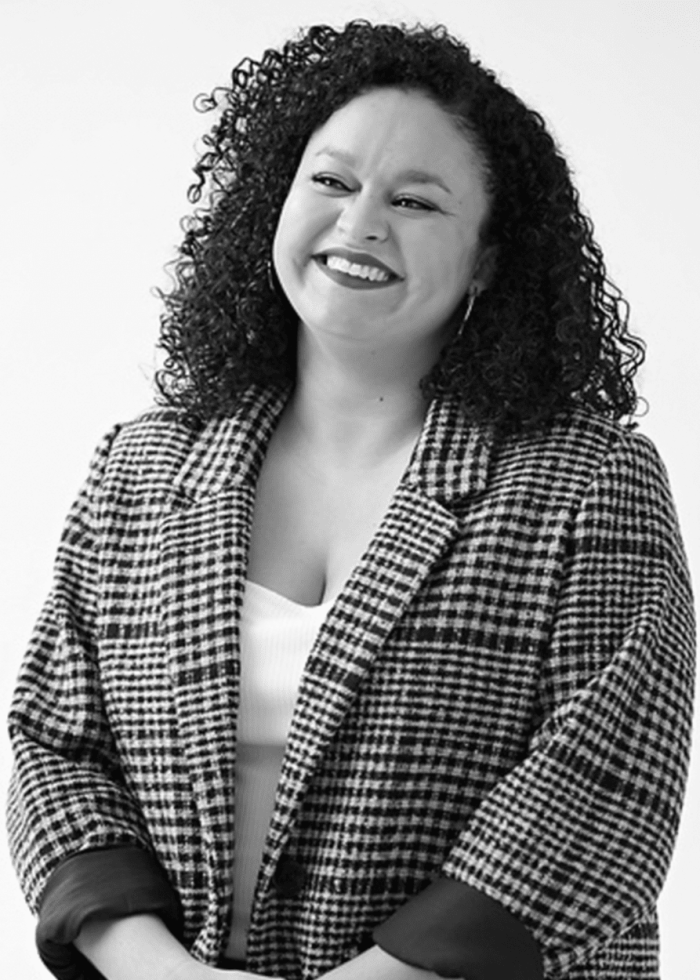 Cristina Angeles smiling, wearing a black and white checkered blazer.